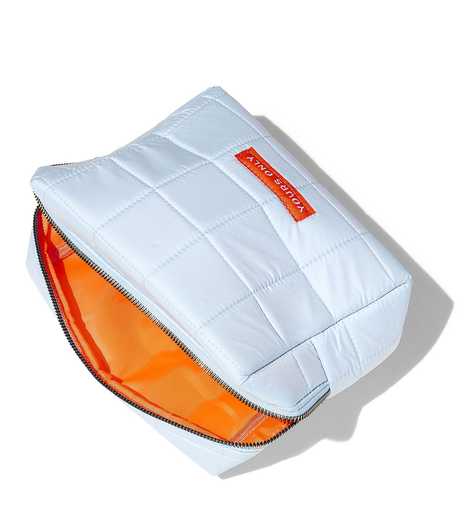 Light blue quilted beauty bag with an orange interior and a red label that says YOURS ONLY
