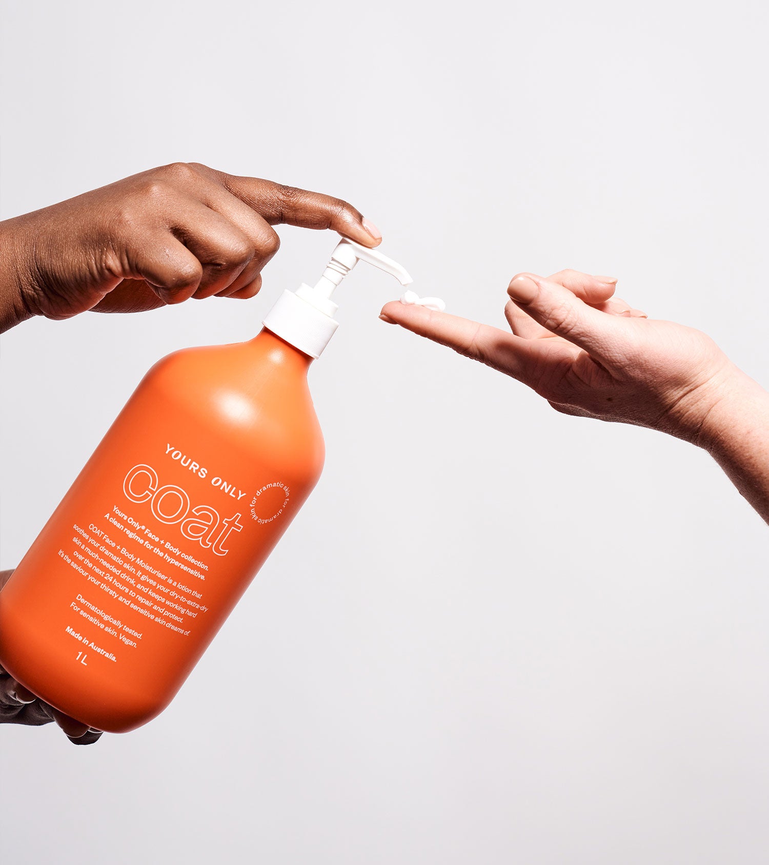Dark-skinned hand pumps Coat moisturiser onto light-skinned hand