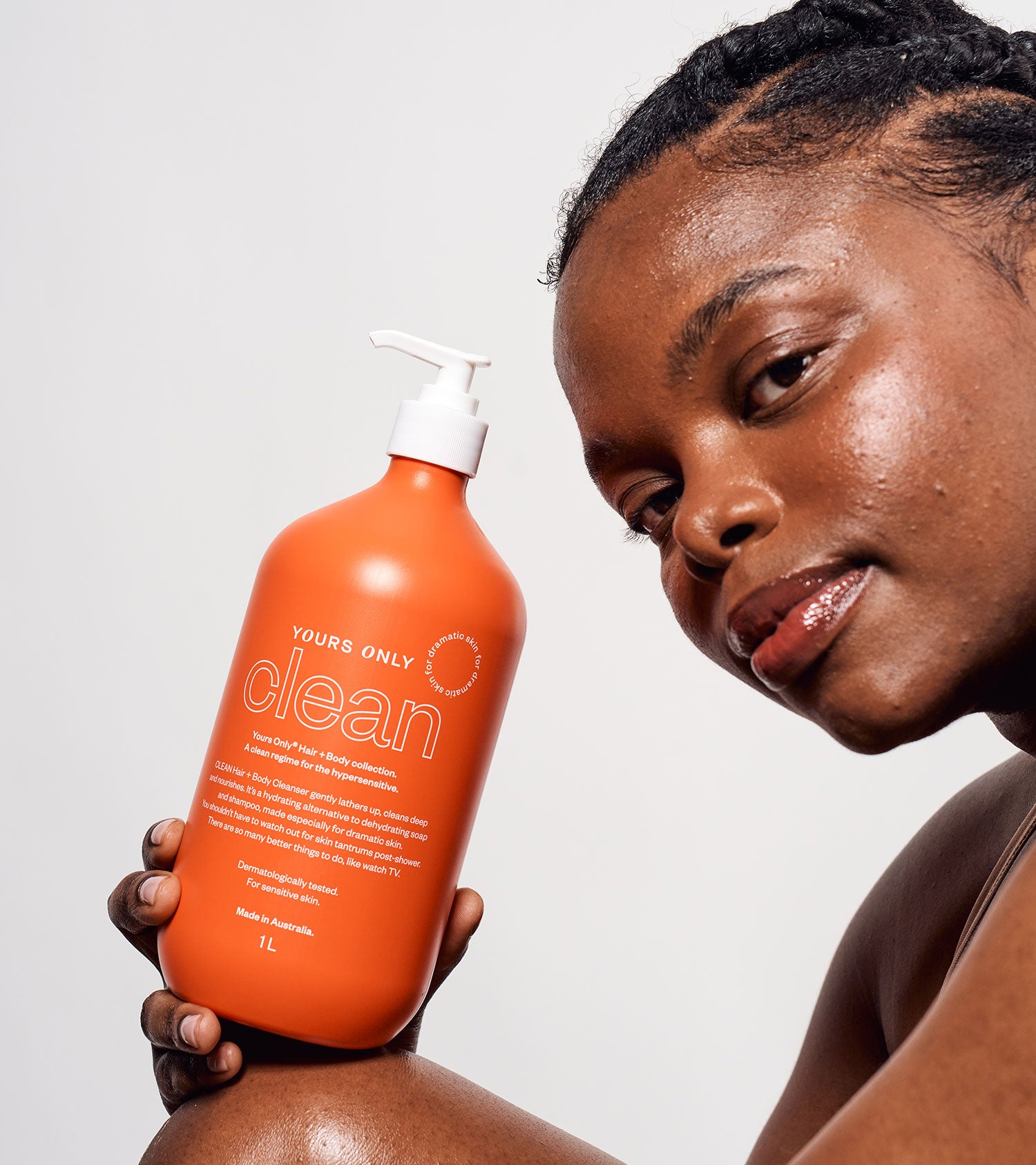 Woman holding a large orange bottle of Yours Only Clean 1L hair and body cleanser