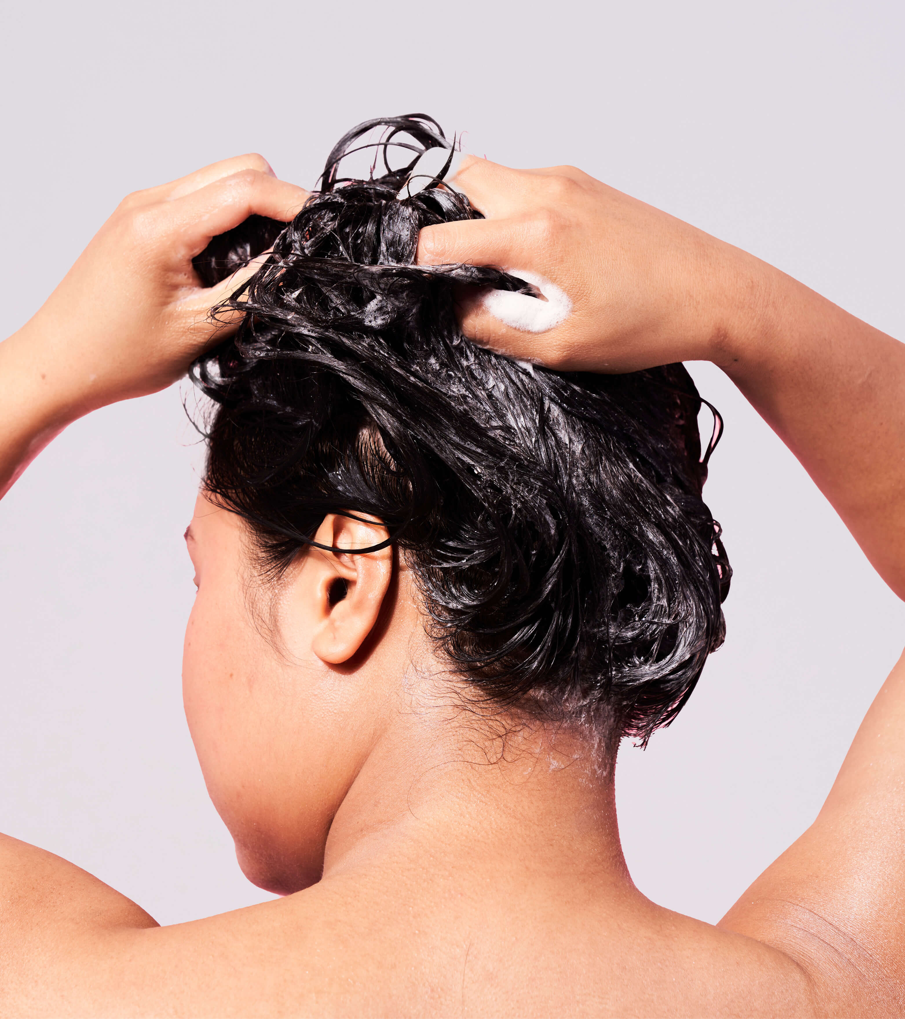 Person washing dark hair with Clean 8 in 1 Hair, Face + Body Cleanser