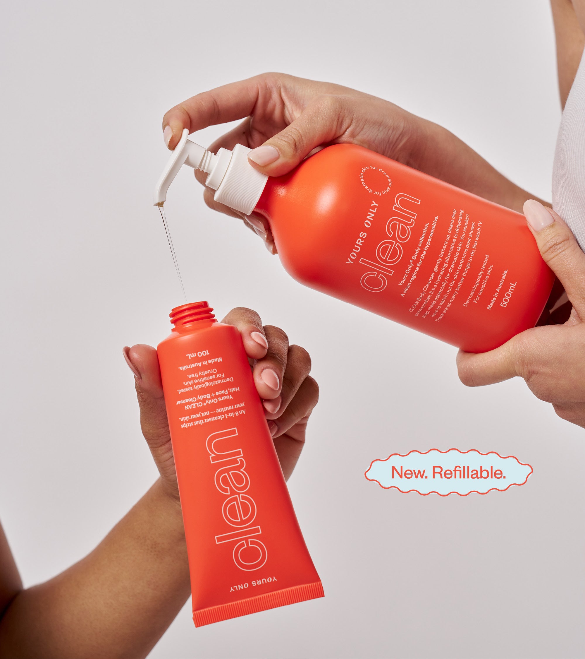 Two hands holding a red 'clean' bottle with a pump, against a light gray background.
