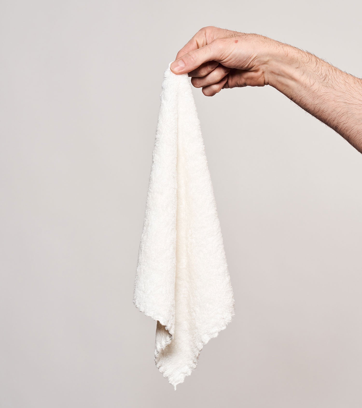 Hand holding a white face cloth gwp