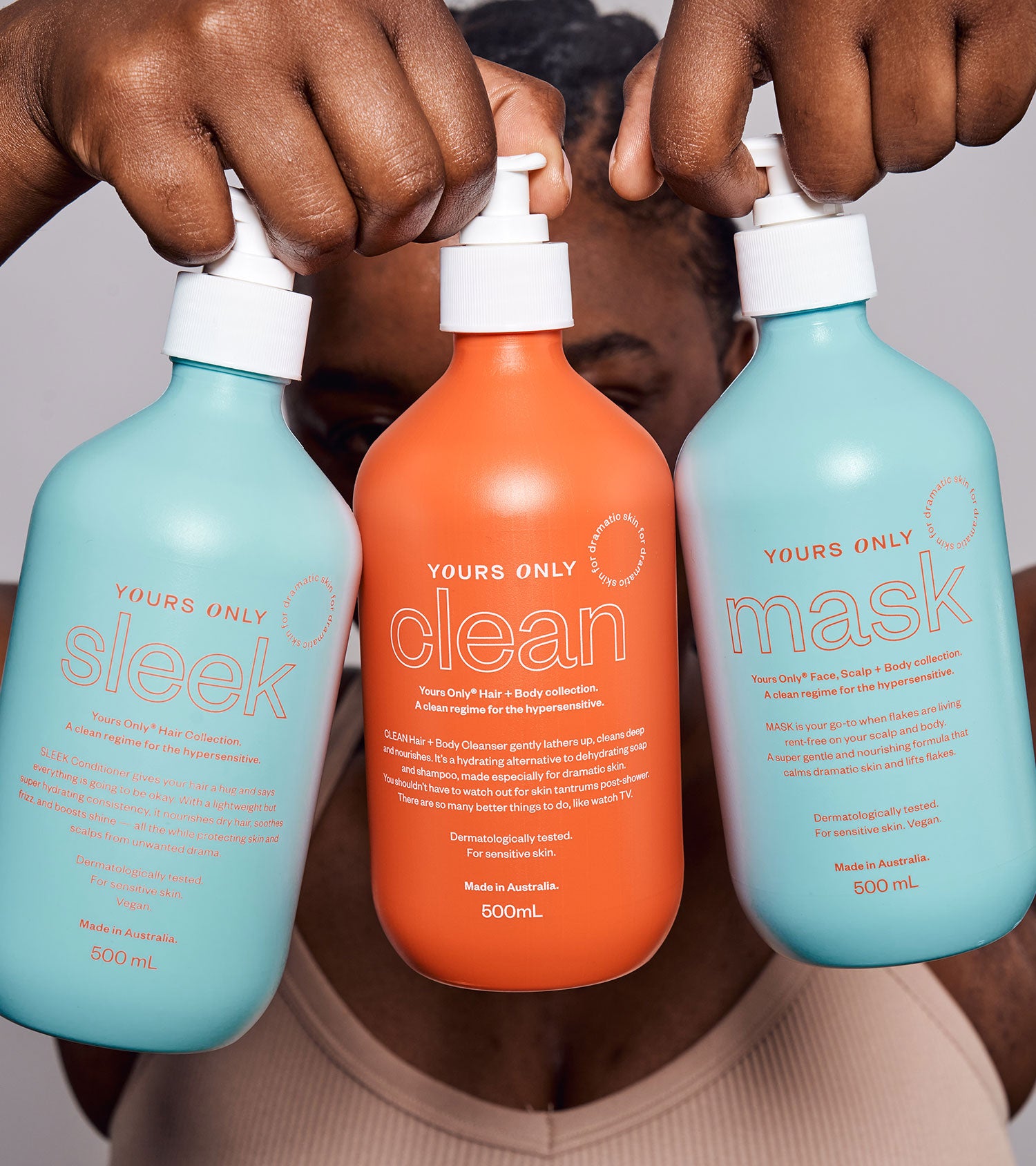 Hands holding three Yours Only hair bundle bottles: Sleek, Clean, and Mask