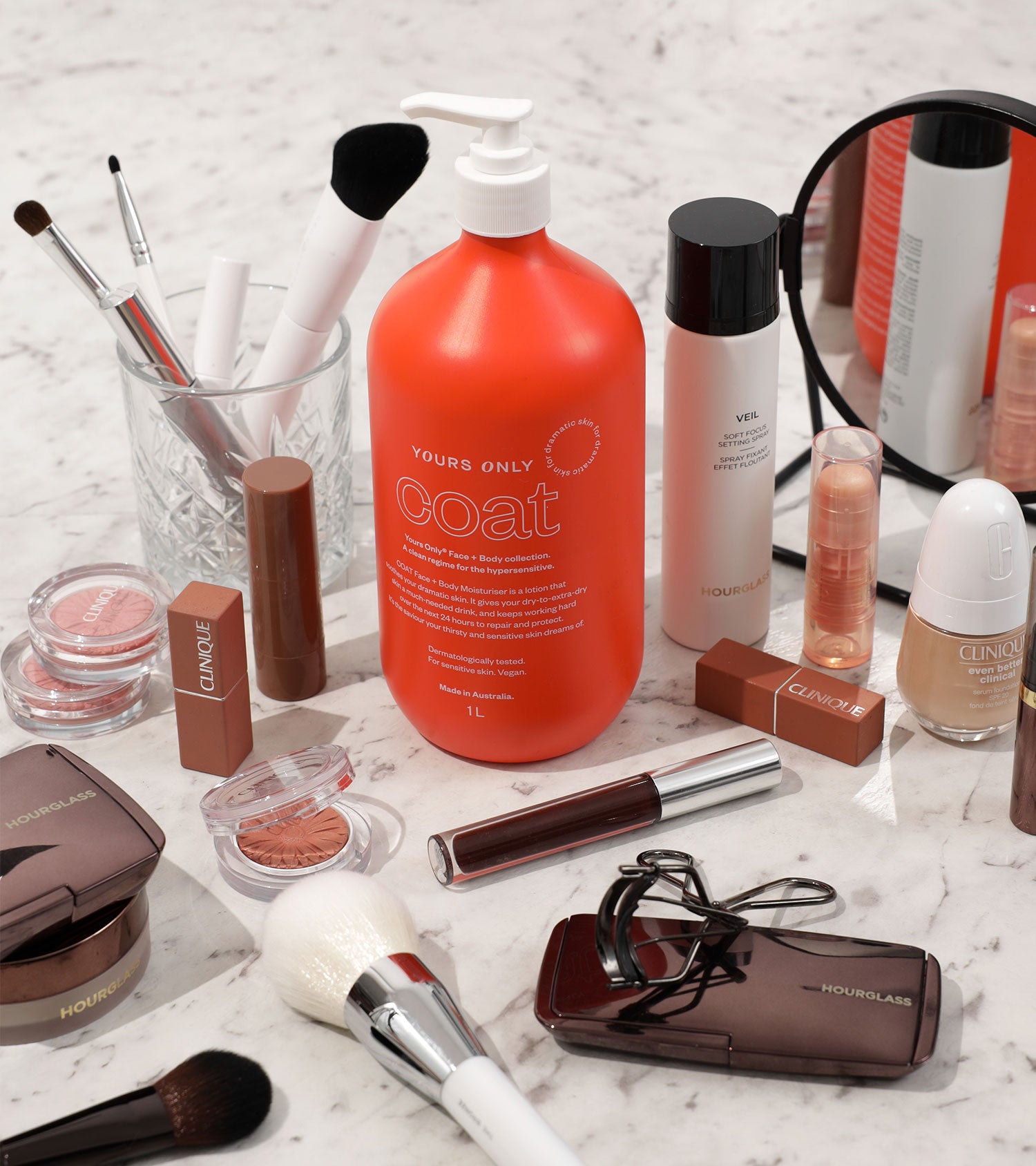 Coat moisturiser 1L with various makeup products and brushes on a marble surface