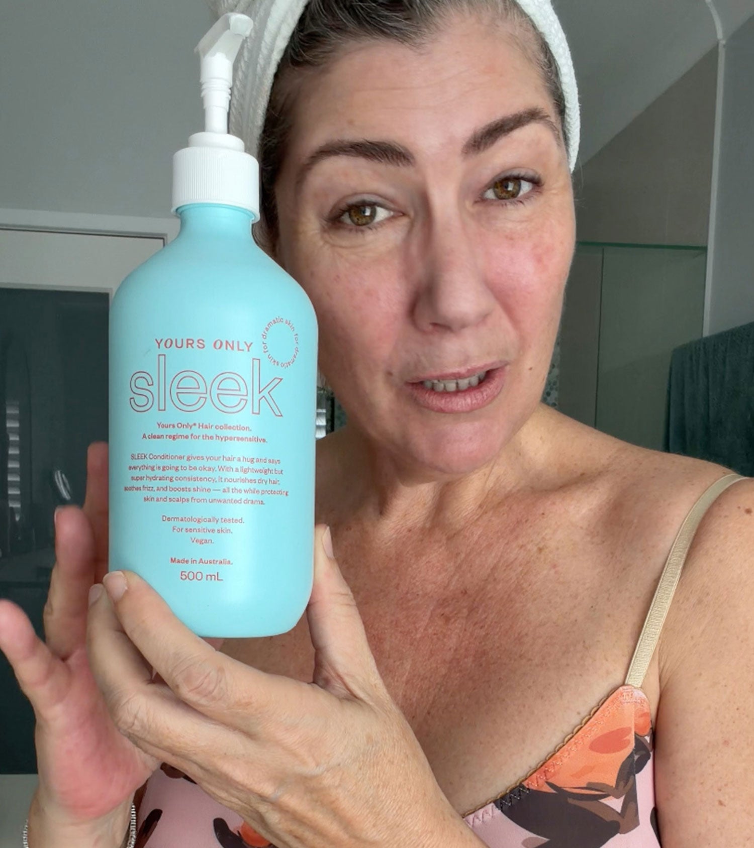 Natalie Angel holding a bottle of Yours Only Sleek conditioner