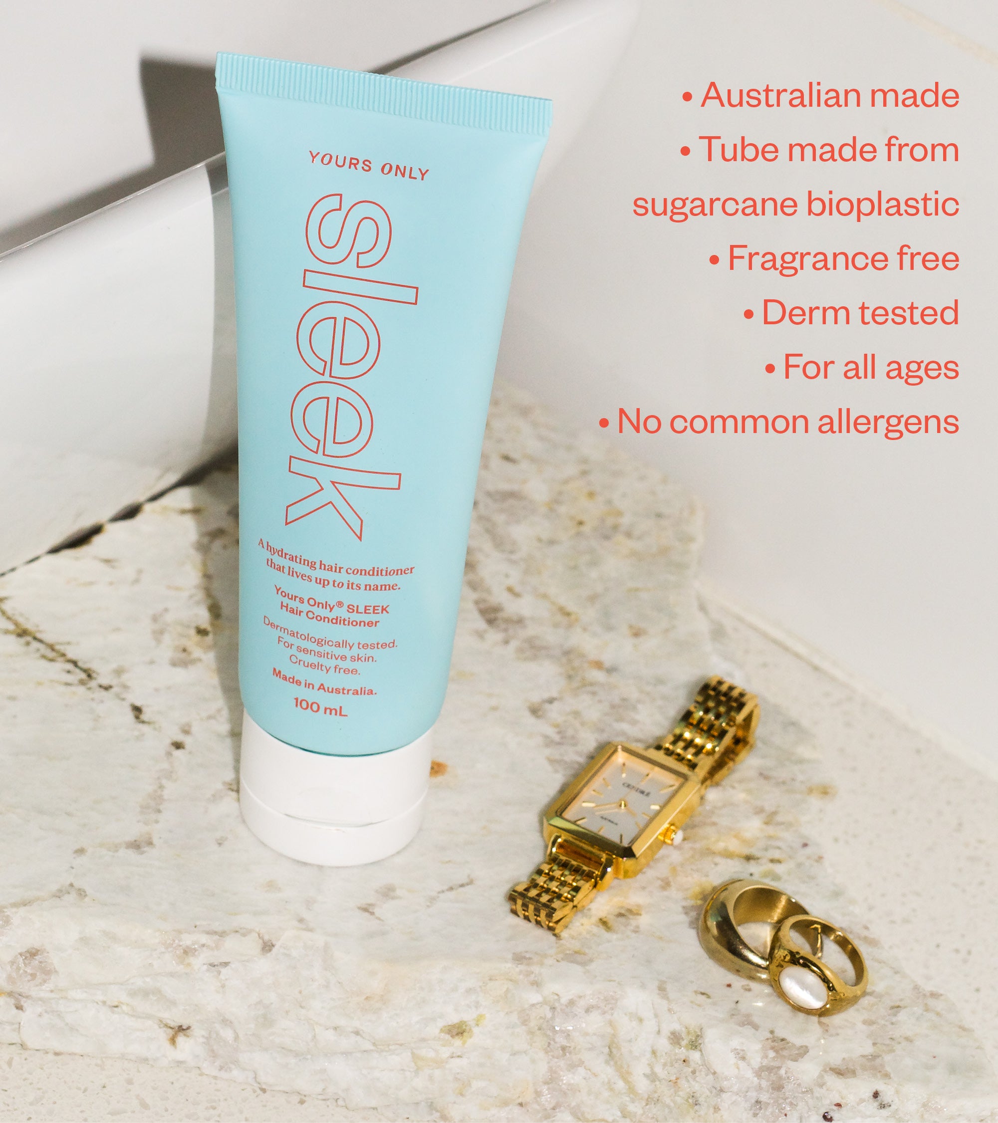 Sleek hair conditioner 100mL tube, gold watch, and two gold rings on a marble surface
