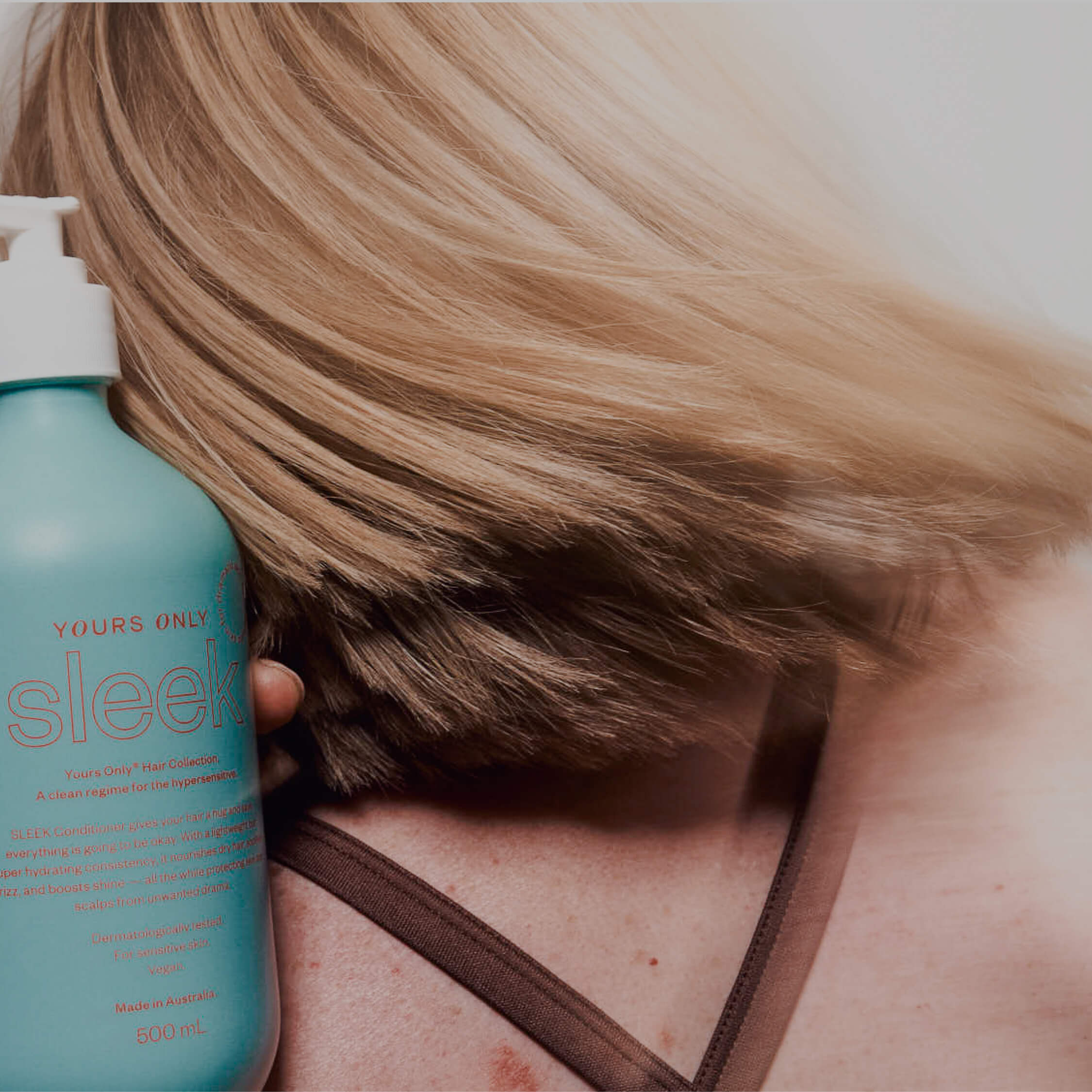 Yours Only Sleek Conditioner bottle held by a person with blonde hair